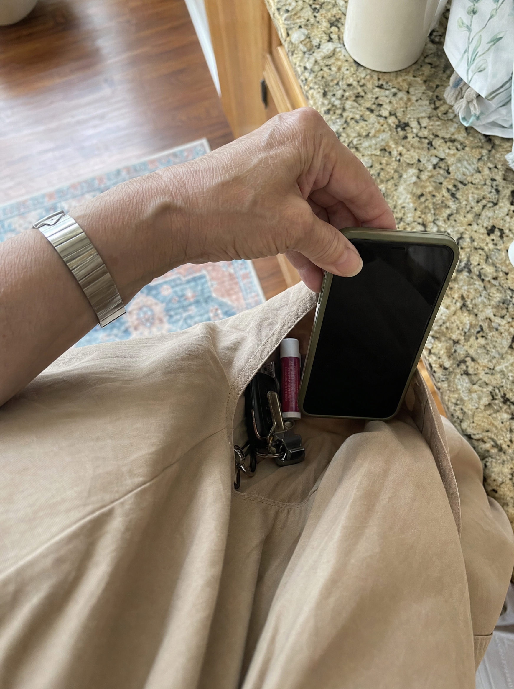 A hand slipping a phone into the deep side pocket of the Kwani