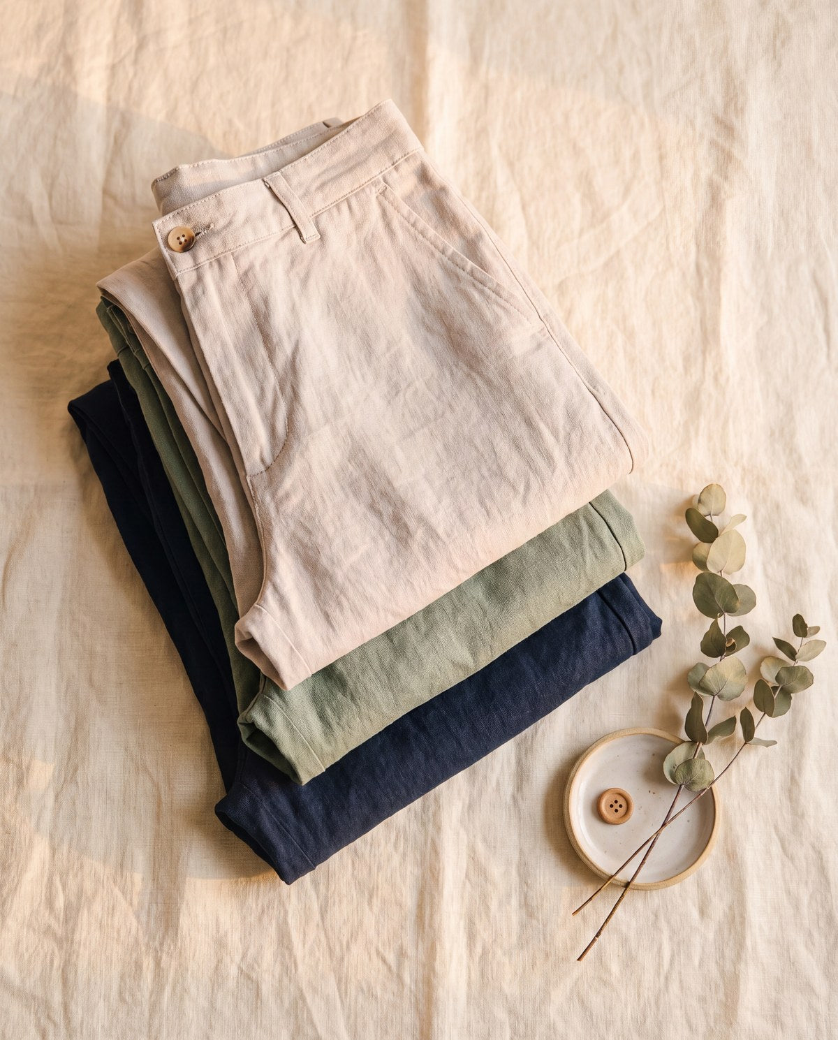 Linen trousers folded in stone, sage and navy
